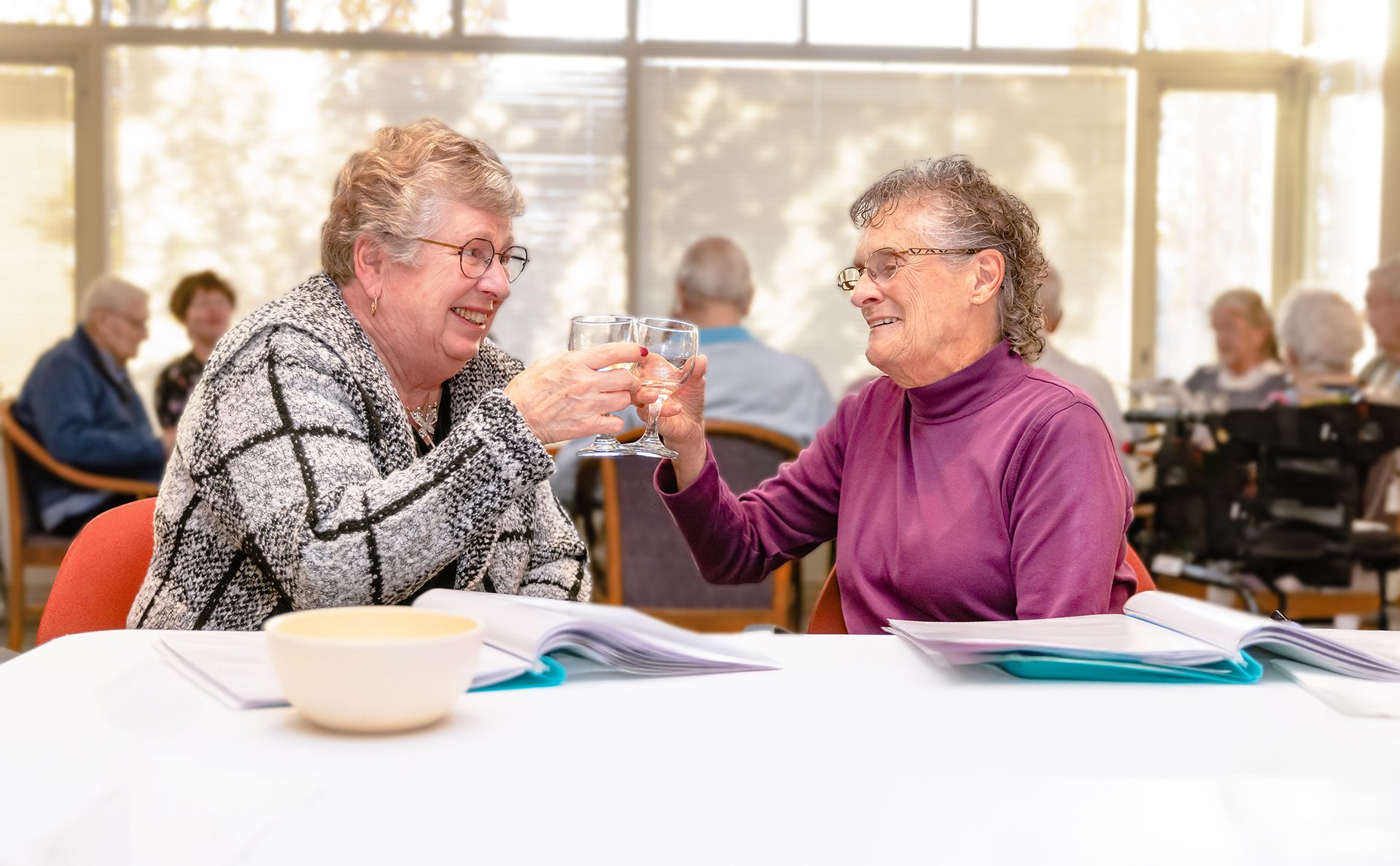 Two women enjoying a cheerful toast at Gardens Retirement Living